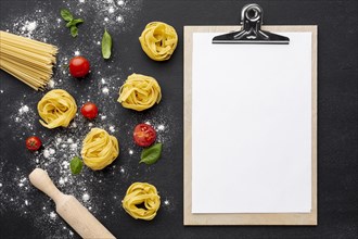 Uncooked tagliatelle spaghetti black background with tomatoes rolling pin clipboard mock up