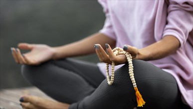 Woman doing yoga outdoors holding rosary