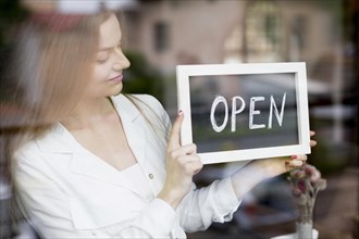 Woman holding open sign coffee shop window