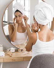 Woman with towel looking into mirror
