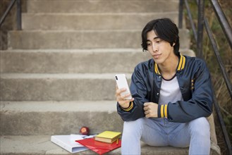Asian teenager sitting with phone stairs