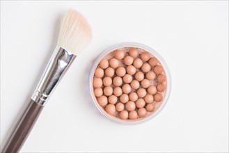 Bronzing pearls with makeup brush white background