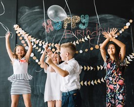 Cheerful kids releasing balloons birthday party