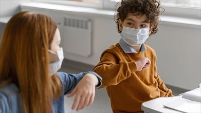 Children with medical masks doing elbow salute class
