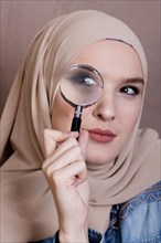 Close up curious muslim woman looking through magnifying glass
