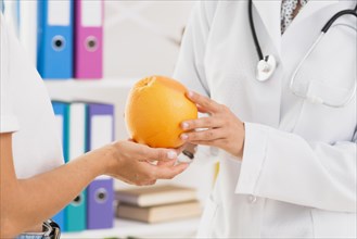 Close up doctor patient holding orange