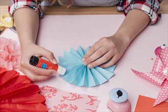 Close up female artist sticking blue origami paper fan