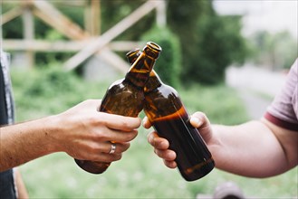 Close up friend s hand toasting brown beer bottles outdoors