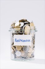Close up retirement glass container full coins white background
