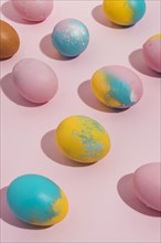 Colorful easter eggs scattered pink table