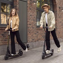 Couple using electric scooters outdoors