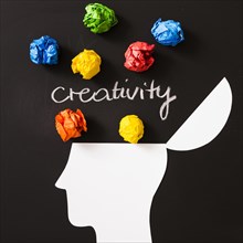 Creativity text with colorful crumpled paper ball open head against black background