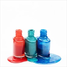 Different shades nail polish spilled around three opened bottles