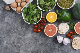 Elevated view vegetables eggs citrus fruit puffed rice cake gray concrete backdrop
