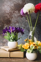 Fake flowers different type vase with wrapped gift boxes against grunge background