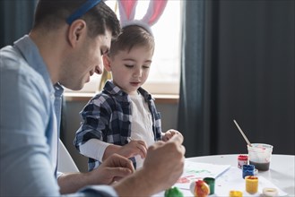 Father showing his son how paint easter eggs
