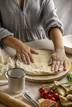 Female chef stretching pizza dough