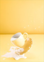 Floating yellow cup with spilling milk