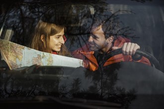 Front view couple with map inside car going road trip
