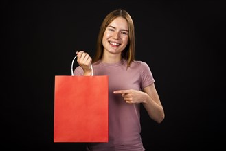 Front view happy woman pointing her red shopping bag