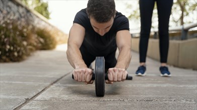 Front view man exercising with ab wheel outside