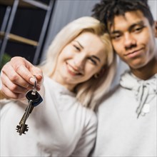 Girlfriend with her boyfriend showing house key toward camera