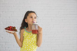 Girl holding plate red strawberries drinking strawberry smoothies