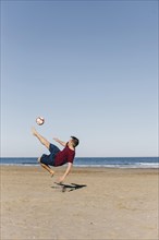 Guy playing football beach