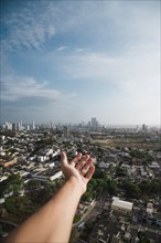 Hand reaching out towards city skyline
