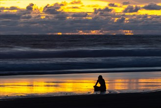 Woman meditating at sunset on sandy beach