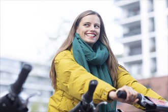Young woman with bike at a bike station renting a bike in the city
