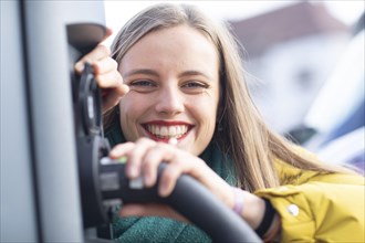 Young woman with charging cable at an e-car station