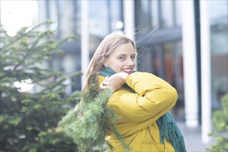 Young woman with green branch in front of town house as environmental protection