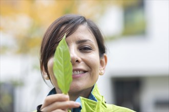 Woman with a plant in front of her face Environmental protection