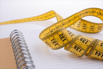 Measuring tape near a notebook on a white background