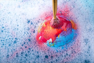 Paint dissolving through painting brush on the top of globe
