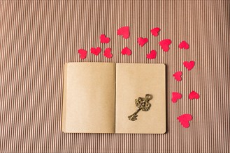 Paper hearts around notebook with a decorative retro key