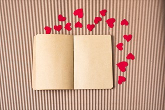 Paper hearts around notebook on cardboard