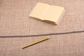 Pencil and notebook with a chain in the middle on spiral notebooks