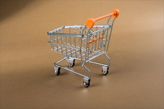 Little model shopping trolley on brown background