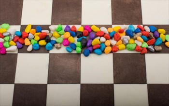 Colorful pebbles spread on checked board background