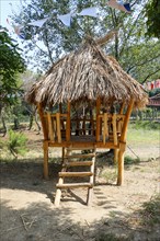 Little wooden hut with sraw roof on soil ground
