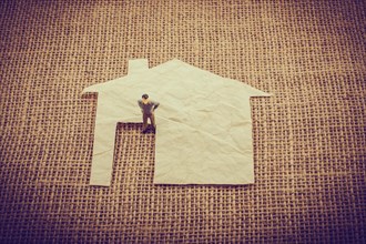 Man figurine and a house shape cut out of paper