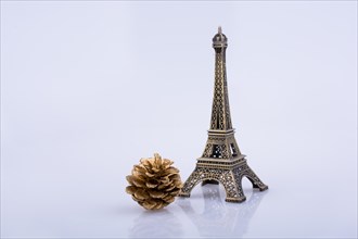 Little model Eiffel Tower and pine coneon a white background