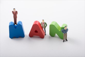 Tiny figurine of men beside colorful wooden letters say MAN
