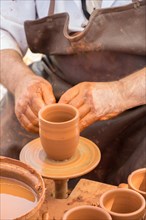 Potter's hands shaping up the clay of the pot