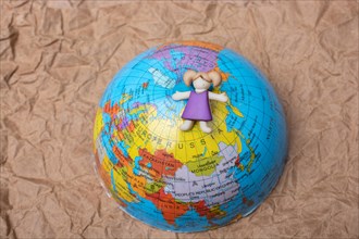 Miniature girl on top of globe as education and business concept