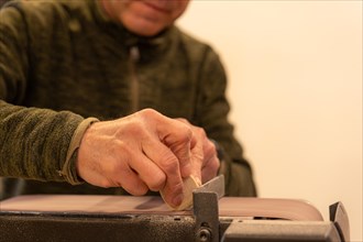 Close-up of an elder artisan polishing by hand a piece of wood