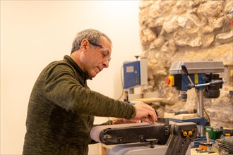 Man using a machine to polish a piece of wood in an artisan workshop