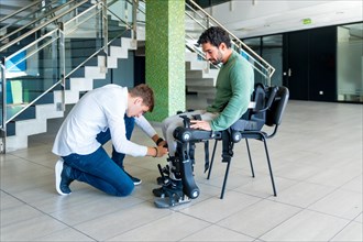 Mechanical exoskeleton. Physiotherapy in a modern hospital: Physiotherapist placing the tapes on the knees of the disabled person to place his robotic skeleton